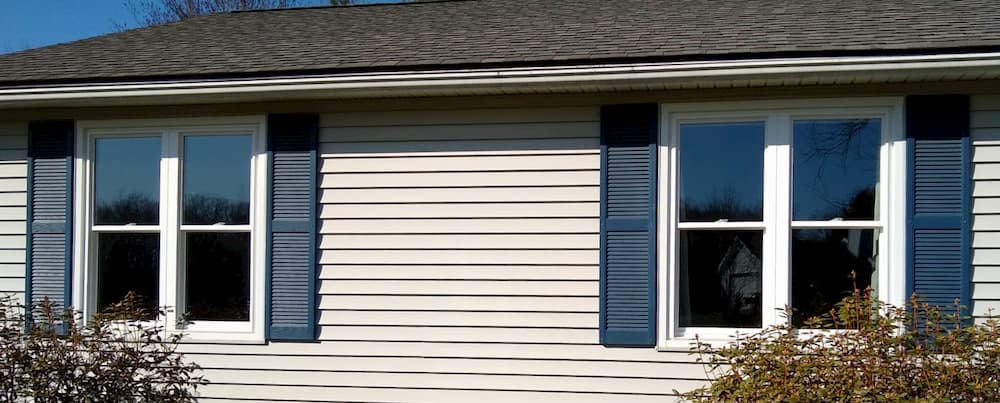 Exterior view of two sets of twin double-hung windows each framed by shutters