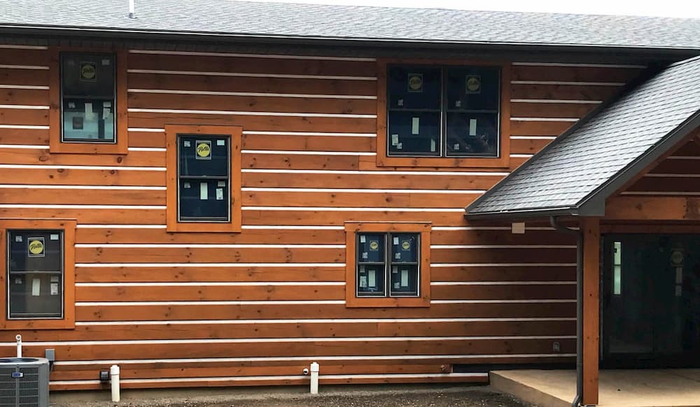 Exterior view of log home with new wood double-hung windows