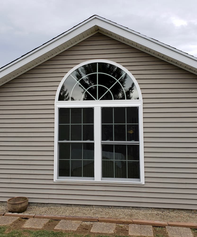 Exterior view of two new vinyl double-hung windows topped with a new arch window.