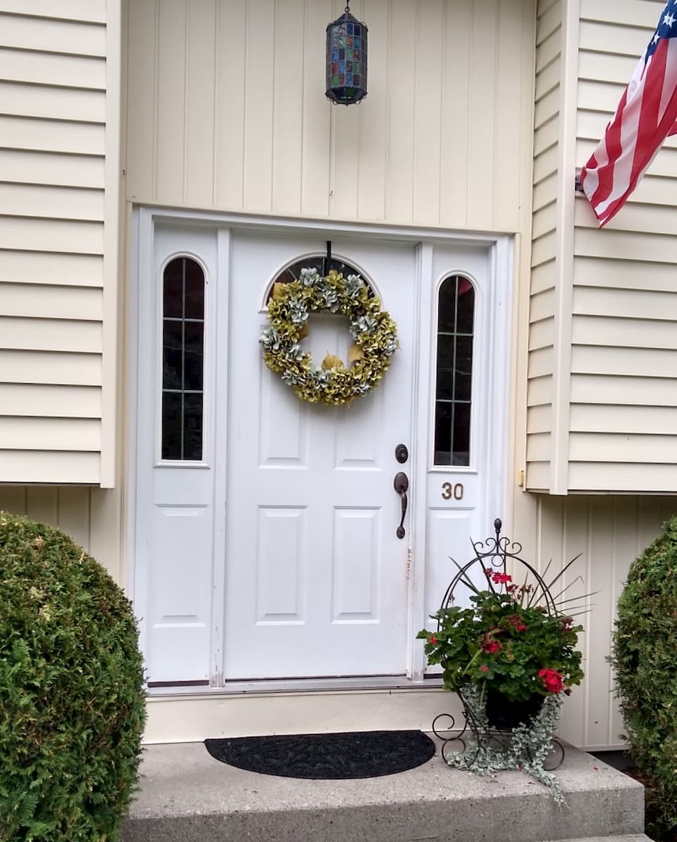 Exterior view of old white entry door with sidelights