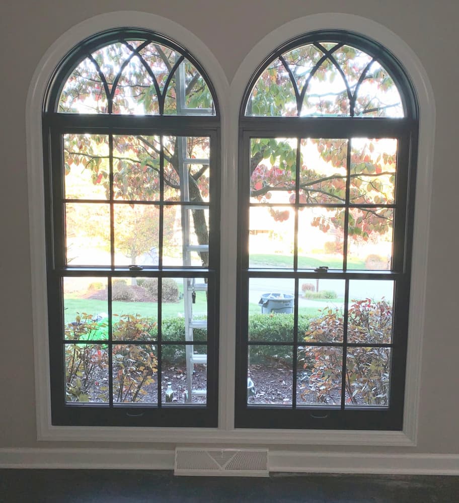 Interior view of black double-hung windows with traditional grille patterns and half-arch transoms