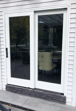 Exterior view of new wood sliding patio door with white finish and no grille pattern