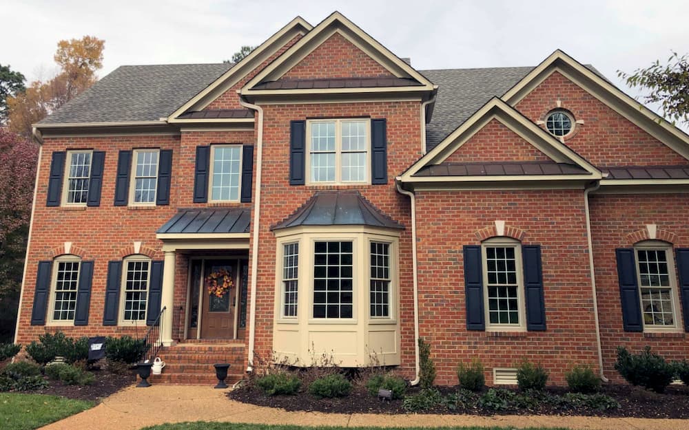 Exterior view of two-story red brick home with new wood double-hung windows