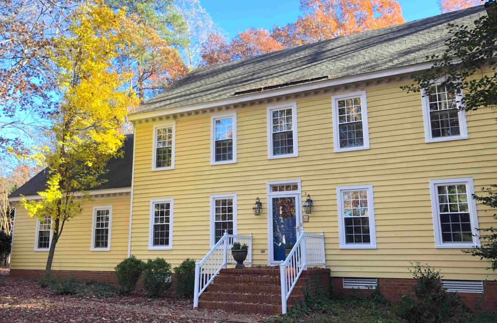 Front exterior view of yellow home with new white vinyl double-hung windows