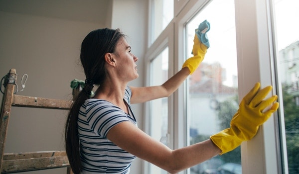 Woman cleans interior of windows with cloth