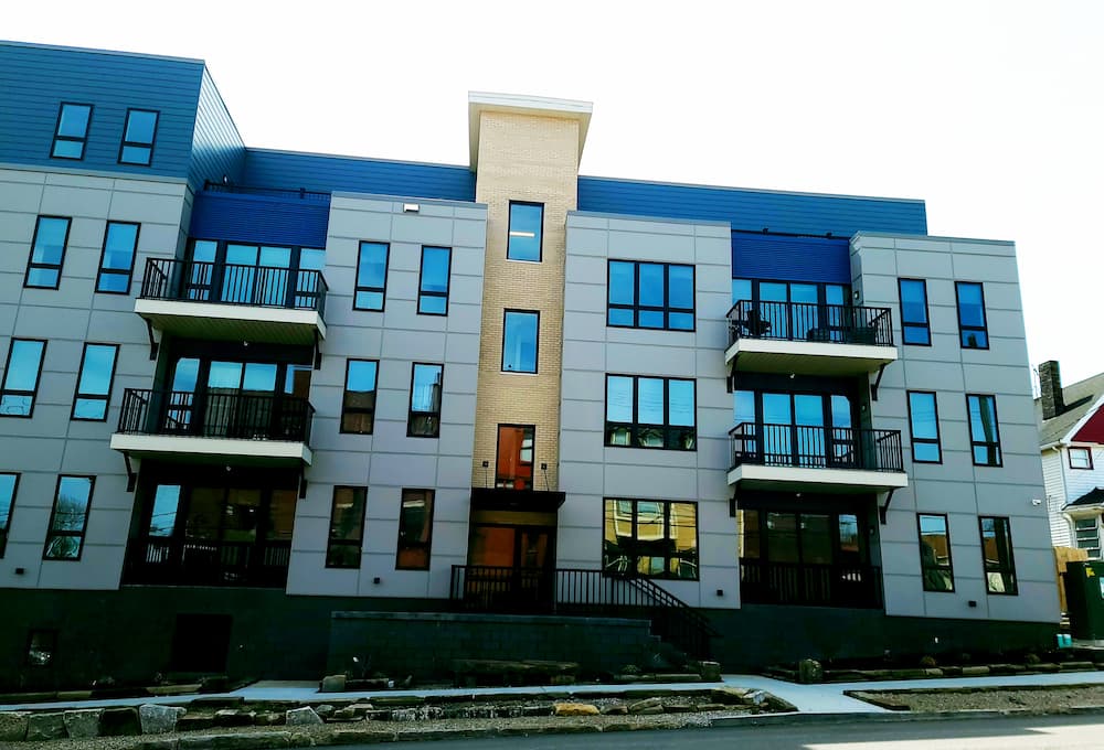 Front of modern apartment building featuring black casement and awning windows