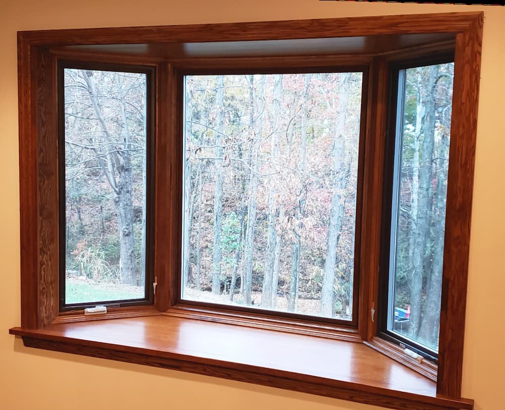 Interior view of new wood bay window overlooking a wooded lot