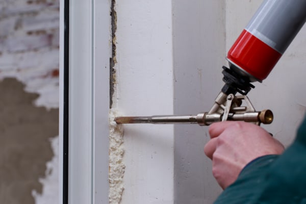 applying special caulking to the exterior seal of a window to prevent drafts