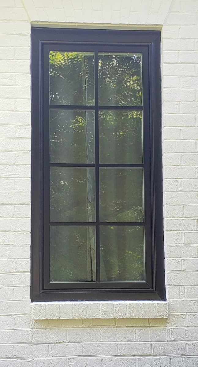 Black casement window on a white brick home