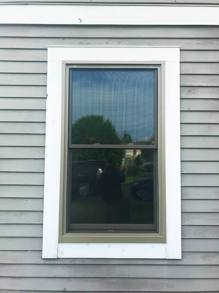 New double-hung window on home with gray siding