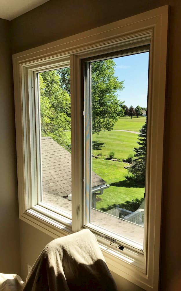 Interior photo of new wood side-by-side casement windows overlooking a golf course