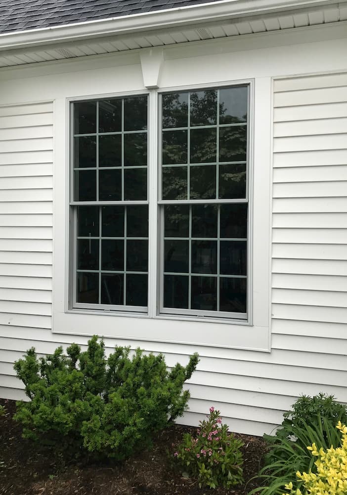 Exterior view of two new double-hung windows on a home with white siding