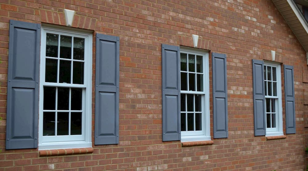 Exterior view of three wood double-hung windows with traditional grille pattern