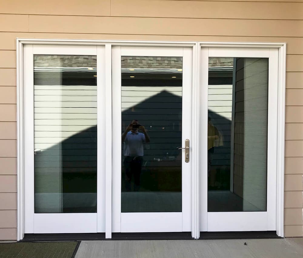 Exterior view of new wood hinged patio door on a home with tan siding