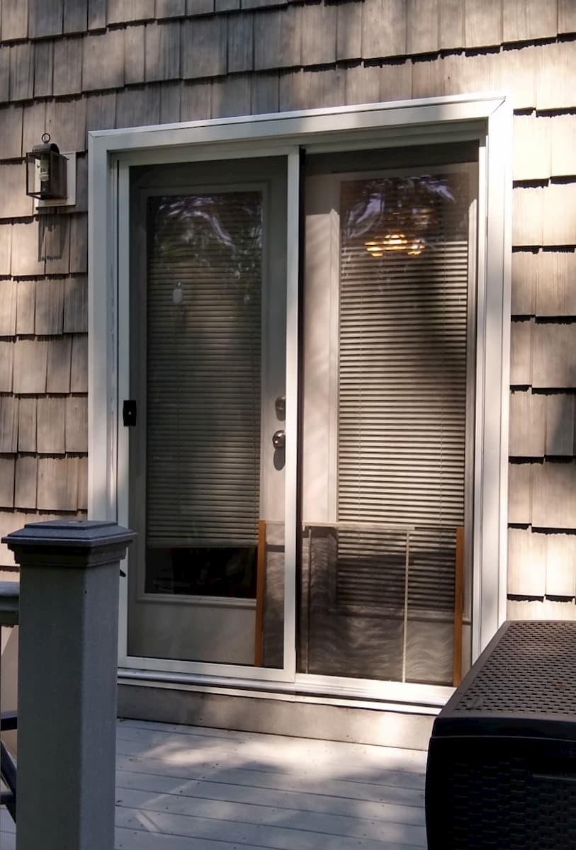 Exterior view of old hinged patio door on shingle-style home