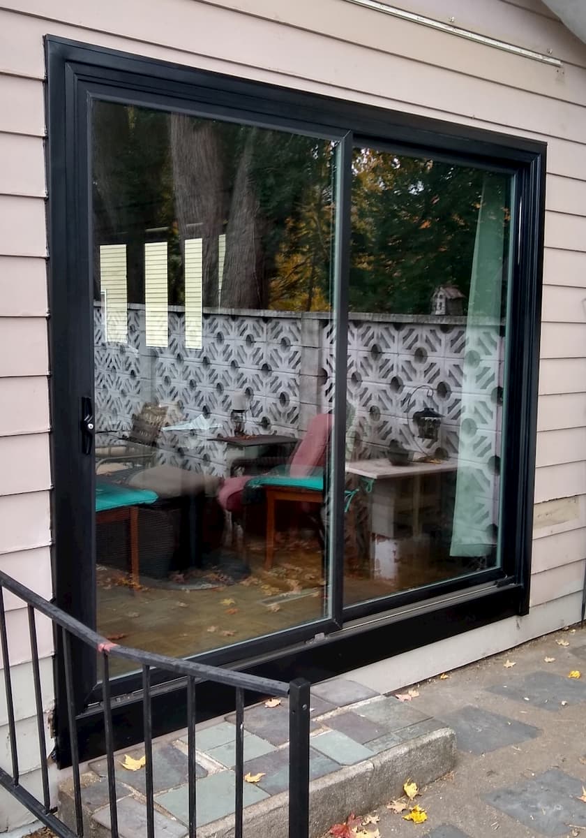Exterior view of new fiberglass sliding patio door on a home with brown siding.