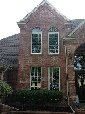 two story brick home with four large white windows