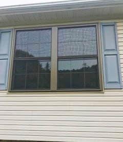 Exterior view of two new wood double-hung windows with traditional grille patterns
