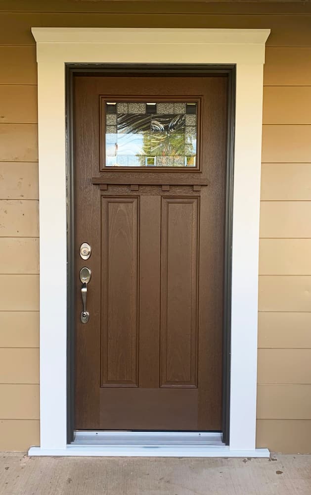 New wood-look Craftsman-style fiberglass entry door with decorative glass