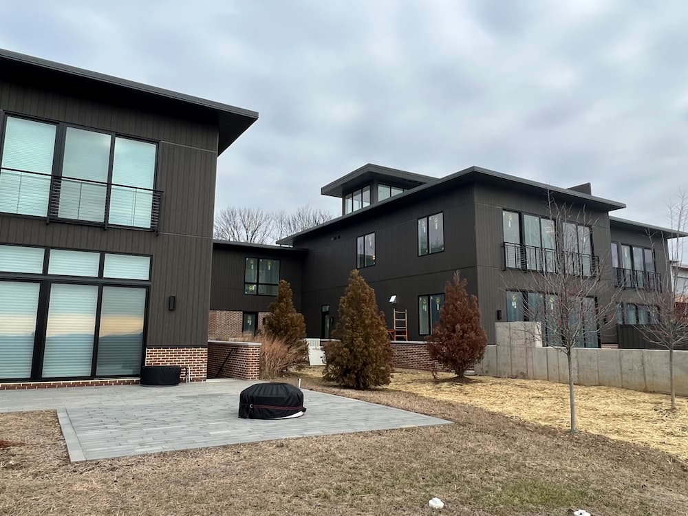 All black, modern townhome building with walls of casement windows and sliding patio doors