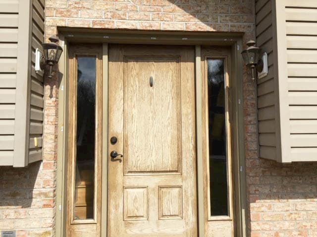 Old, worn-down wood entry door with two full-length sidelights