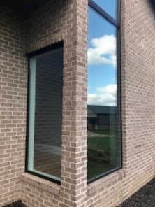 Exterior view of new fiberglass picture window from Pella on brick home