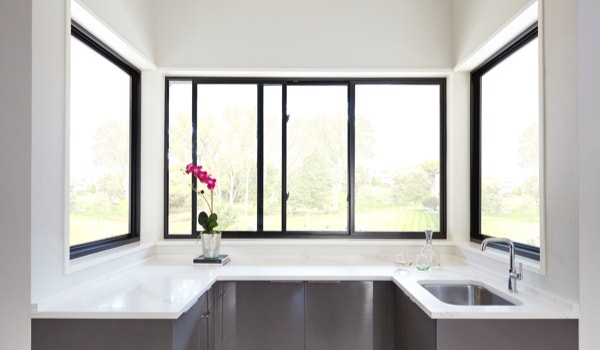 Fiberglass sliding windows dark frame and white walls in kitchen above counter