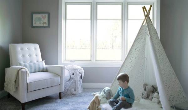 Child plays in bedroom in front of three white, triple-glazed windows