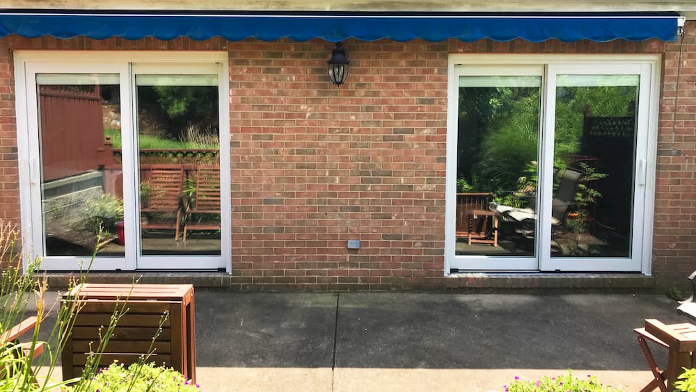 Exterior view of two new wood sliding patio doors on red brick home