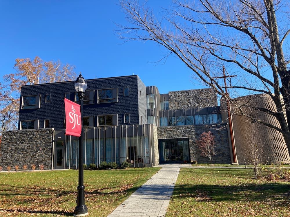 Front view of new university construction featuring gray wood windows and red sign on lightpole