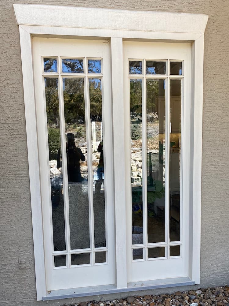 Before photo of white double patio doors with grilles.