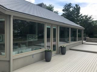 Exterior view of deck and large fixed wood windows with aluminum cladding