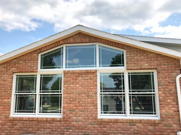 Exterior view of brick home with new wood double-hung and special shape windows.