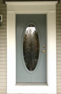 Old gray front entry door with oval window and decorative glass