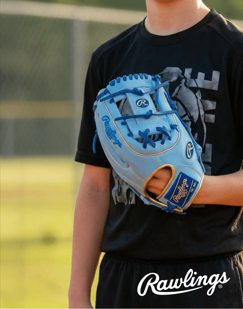 A person wearing a light blue Rawlings Heart of the Hide baseball glove while standing on a baseball field.