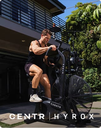 Person exercising on a CENTR HYROX fitness machine outdoors.
