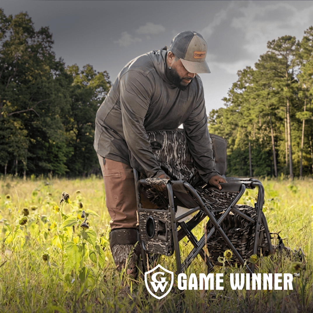 Hunter setting up a portable hunting chair in a grassy field.