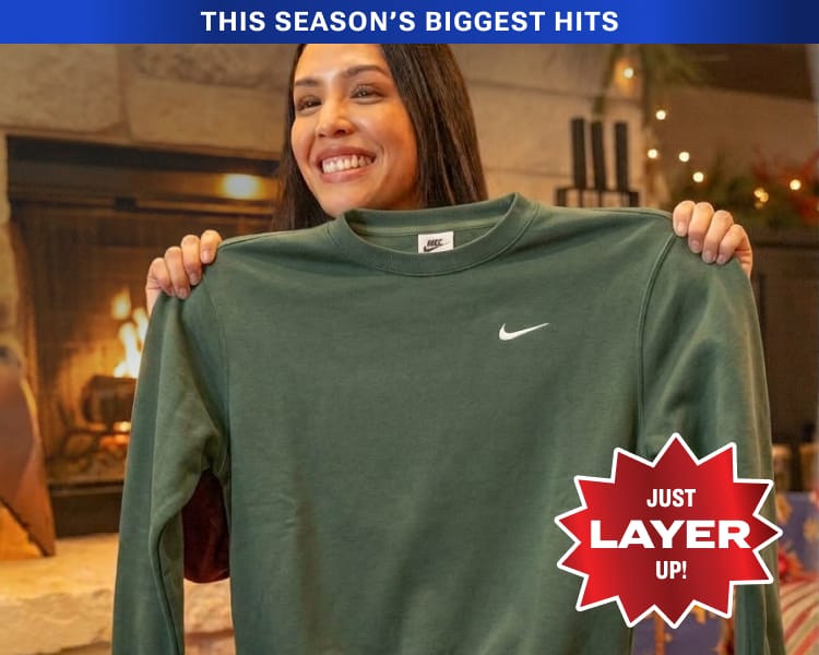 Nike crewneck fleece sweatshirt being held up in front of a person with overlaid badge 'Just Layer Up.'