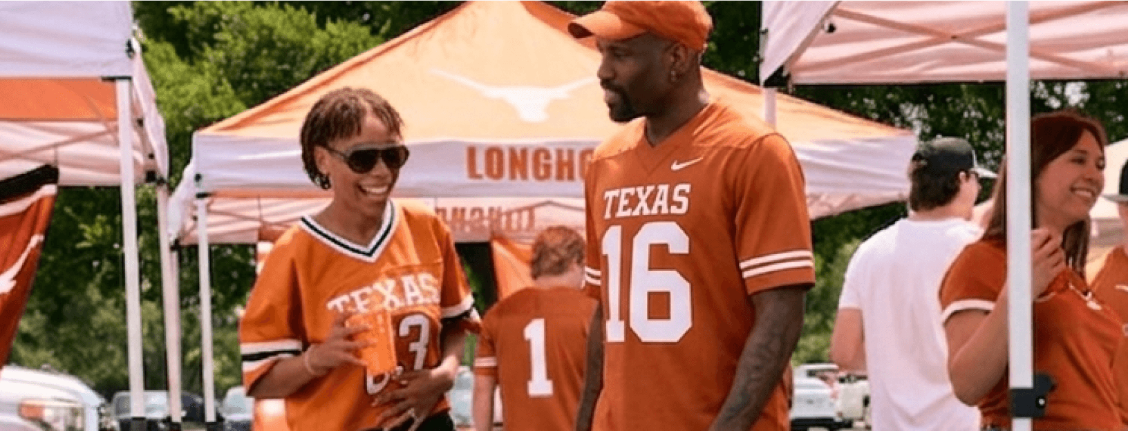 Fans wearing Texas Longhorns jerseys at a tailgate under team canopies.