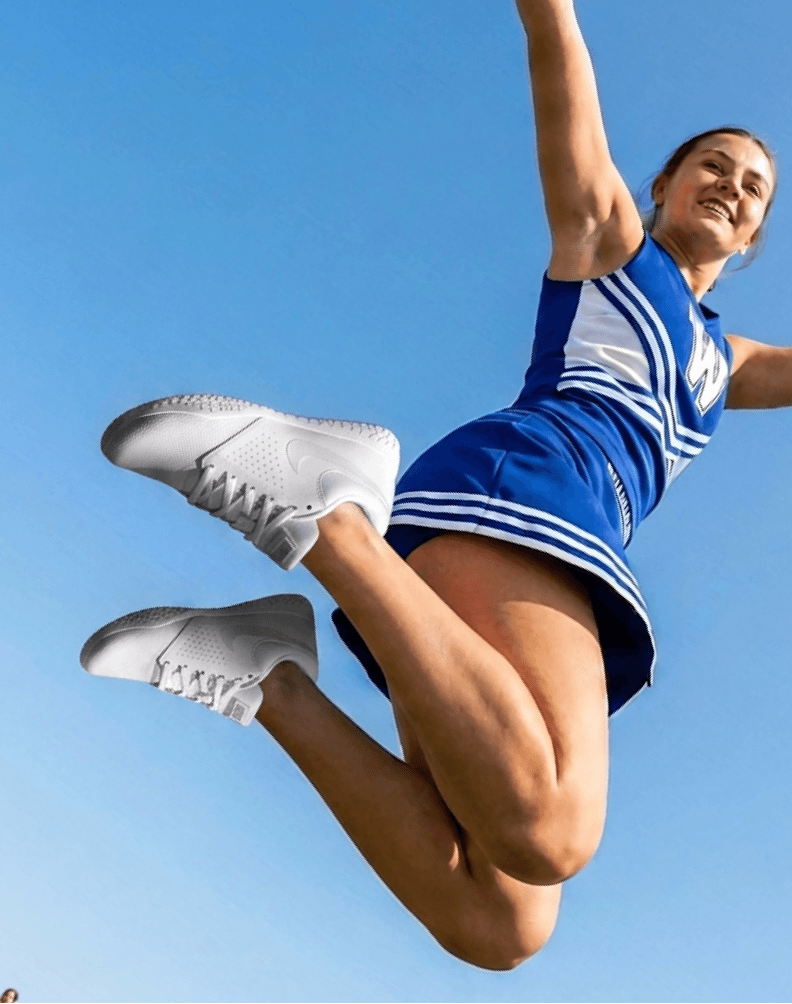 Athlete mid-air wearing a blue cheer uniform and white shoes against a clear sky.