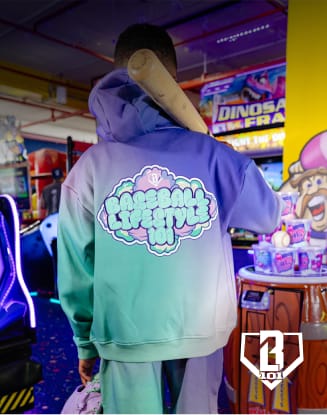 Person wearing a colorful hoodie standing in an arcade surrounded by illuminated game machines.