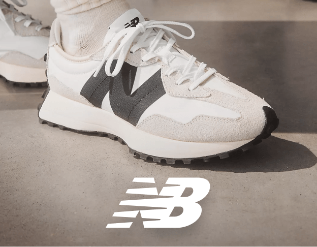 White New Balance sneakers on person sitting outdoors.