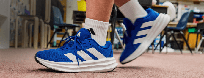 Close up of blue and white athletic shoes on a person's feet. Best Foot Forward: Athletic Shoes and Sneakers.