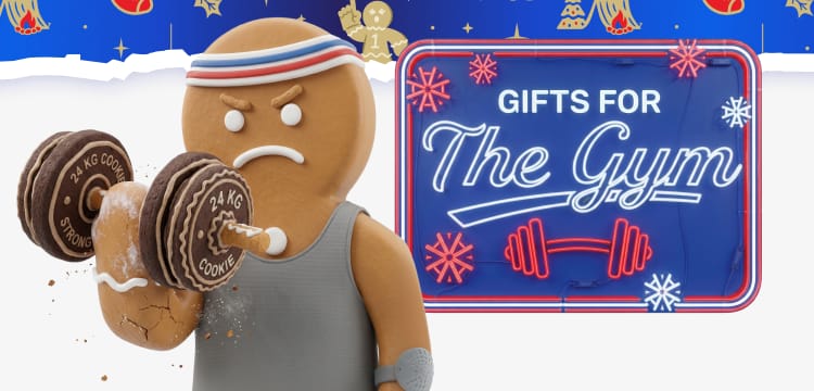 Holiday banner featuring gingerbread cookie weightlifters exercising with cookie dumbbells and a cookie barbell. A neon sign in the center reads Gifts for The Gym. Blue holiday-themed borders with snowflakes and Academy Sports + Outdoors logos appear on both sides.'