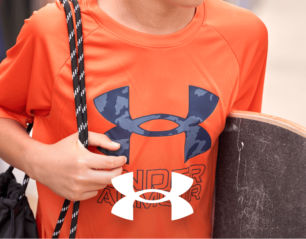 Close-up of a person wearing an orange Under Armour shirt and carrying a black shoulder bag. Under Armour