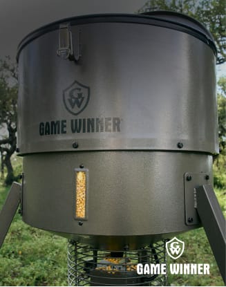 Game Winner deer feeder standing outdoors in a grassy area.