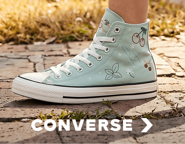 Green Converse high-top sneakers on a dirt ground.