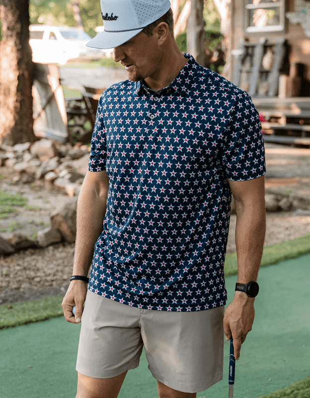 Person wearing a navy blue patterned performance polo shirt outdoors near stone bridge.