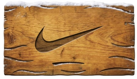 Nike Swoosh carved into a weathered wooden surface topped with snow.