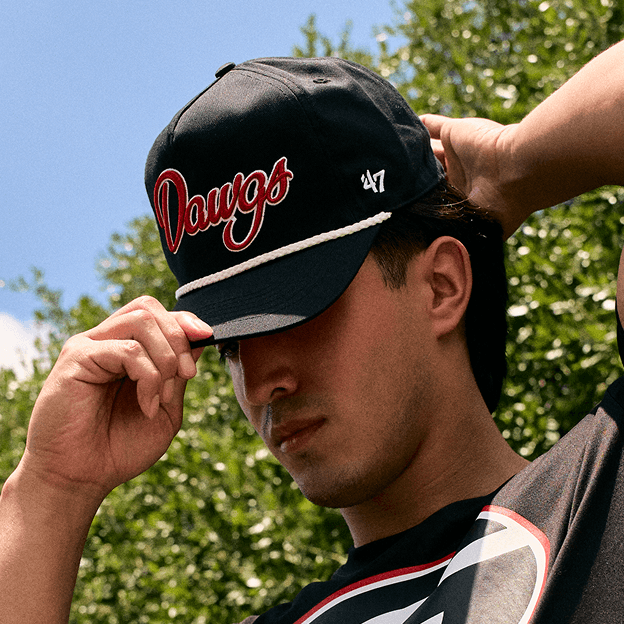 Person adjusting a Georgia Bulldogs collegiate baseball cap outdoors.
